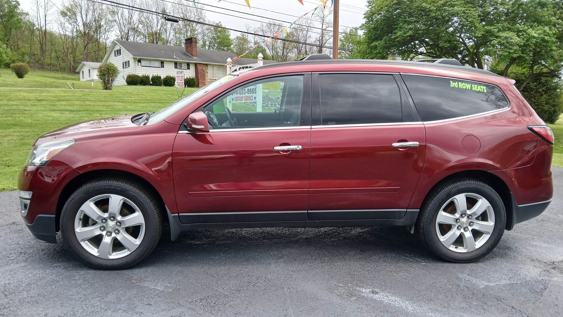 Maroon SUV parked on a paved lot with houses and trees in the background.