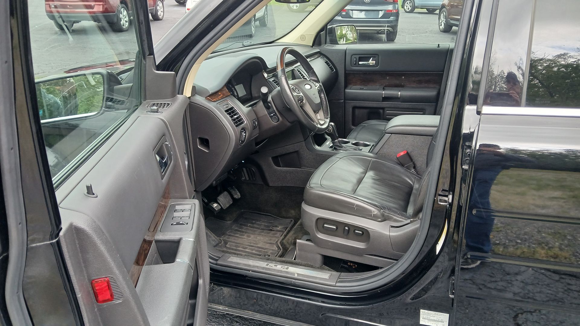 Open driver-side door showing a black SUV interior with gray cloth seats and steering wheel.