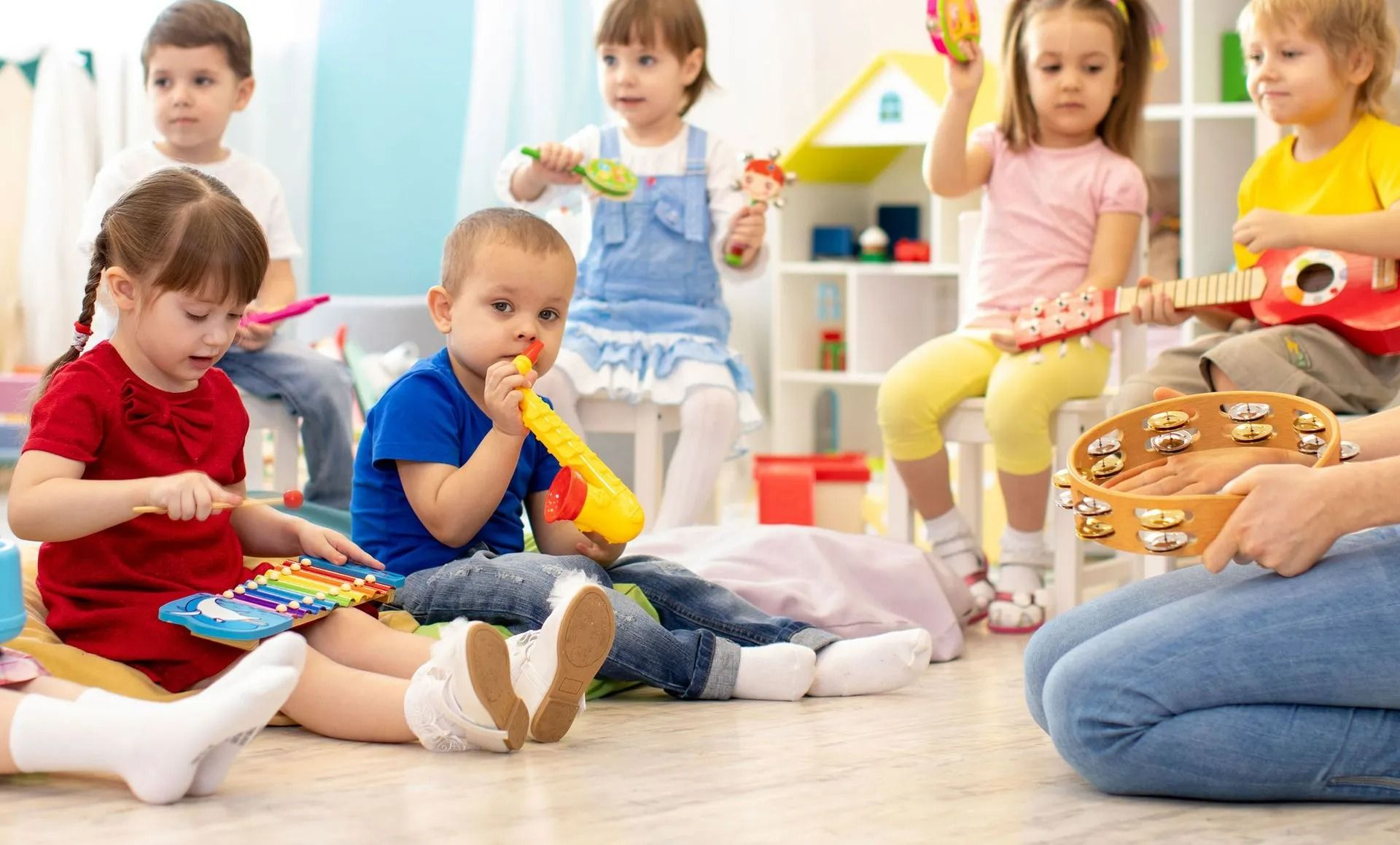 Children sitting on the floor playing with musical toys in a bright classroom