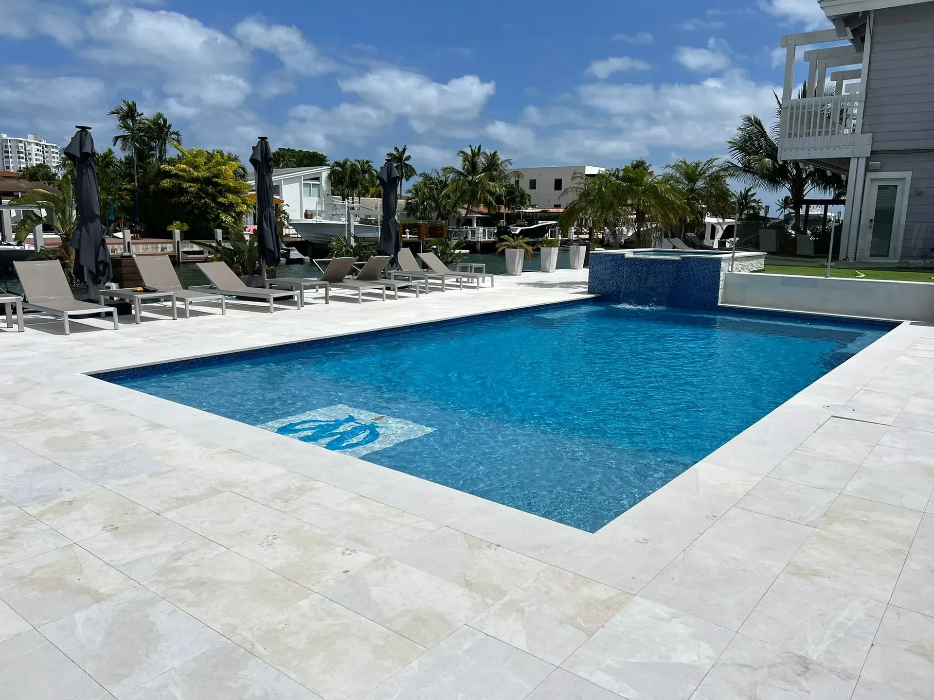 Swimming pool with blue water and surrounding lounge chairs, sunny outdoor setting.
