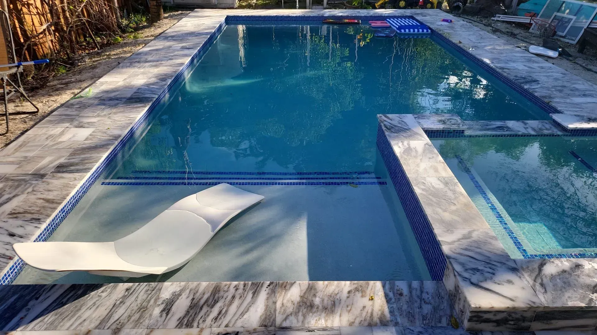 Swimming pool with blue water and marble decking, a submerged lounger, and a connected spa.