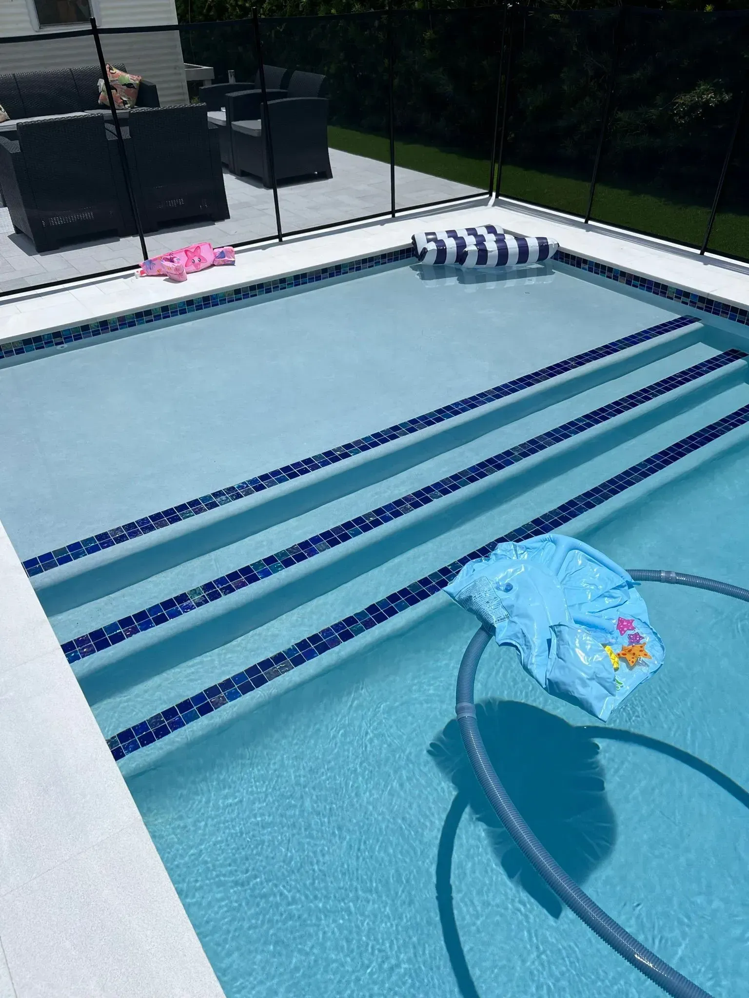 Swimming pool with steps, blue water, and pool toys.