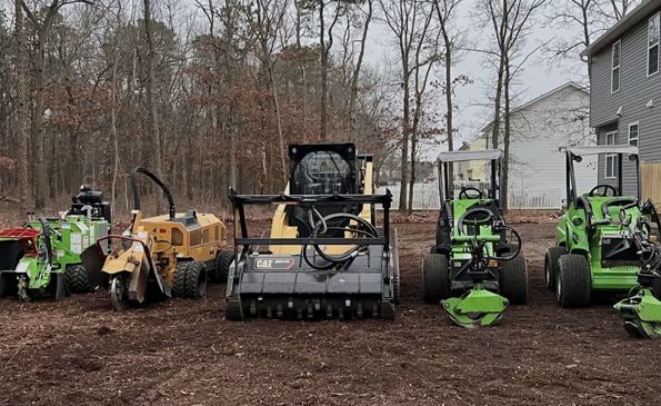 A group of tractors are parked in a yard in front of a house.