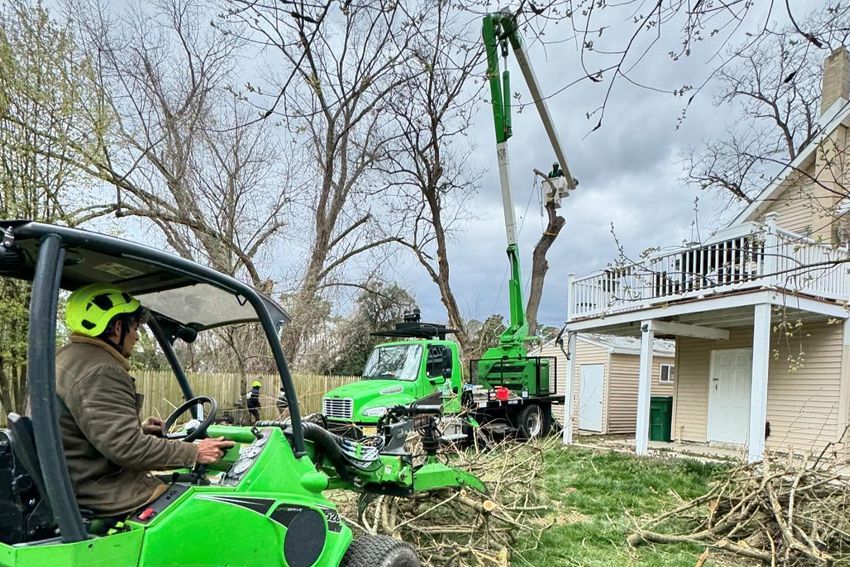 A man is driving a green vehicle in front of a house.