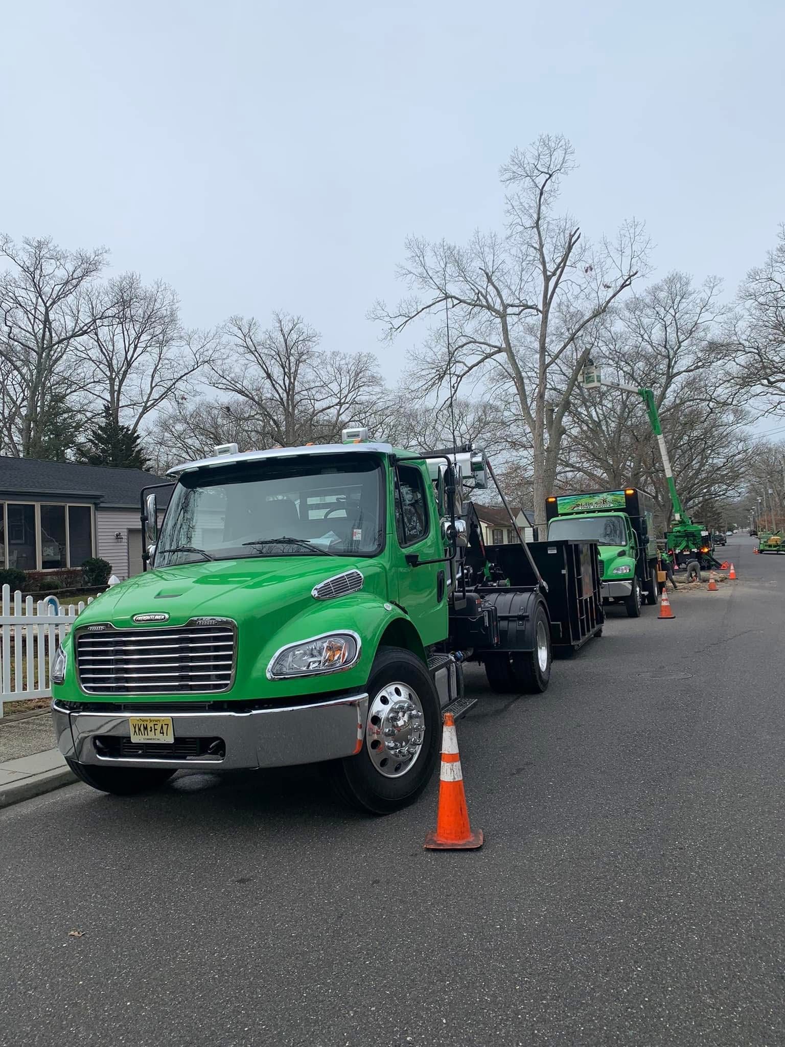 A green truck is parked on the side of the road next to a traffic cone.