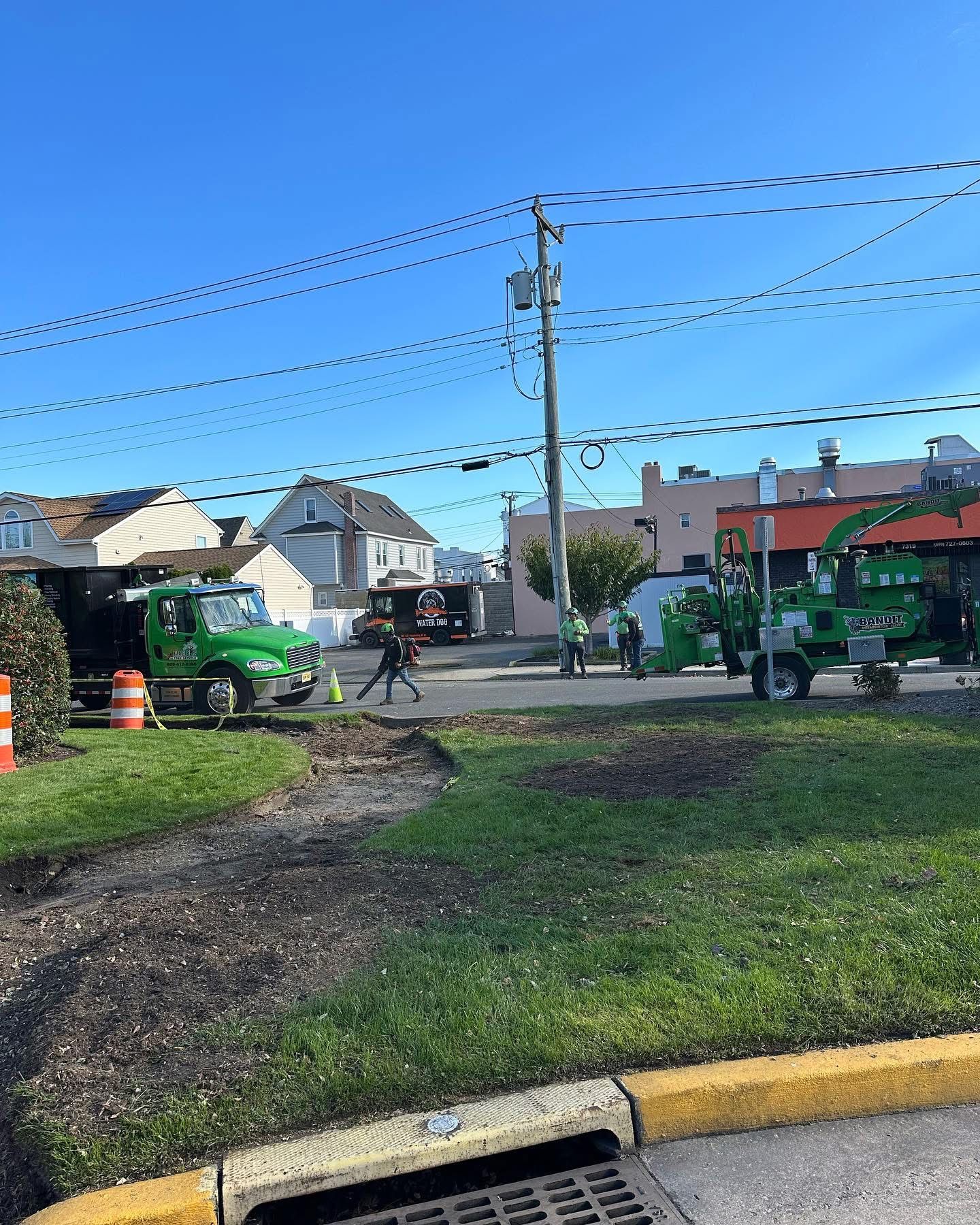 A green truck is parked on the side of the road next to a yellow curb.