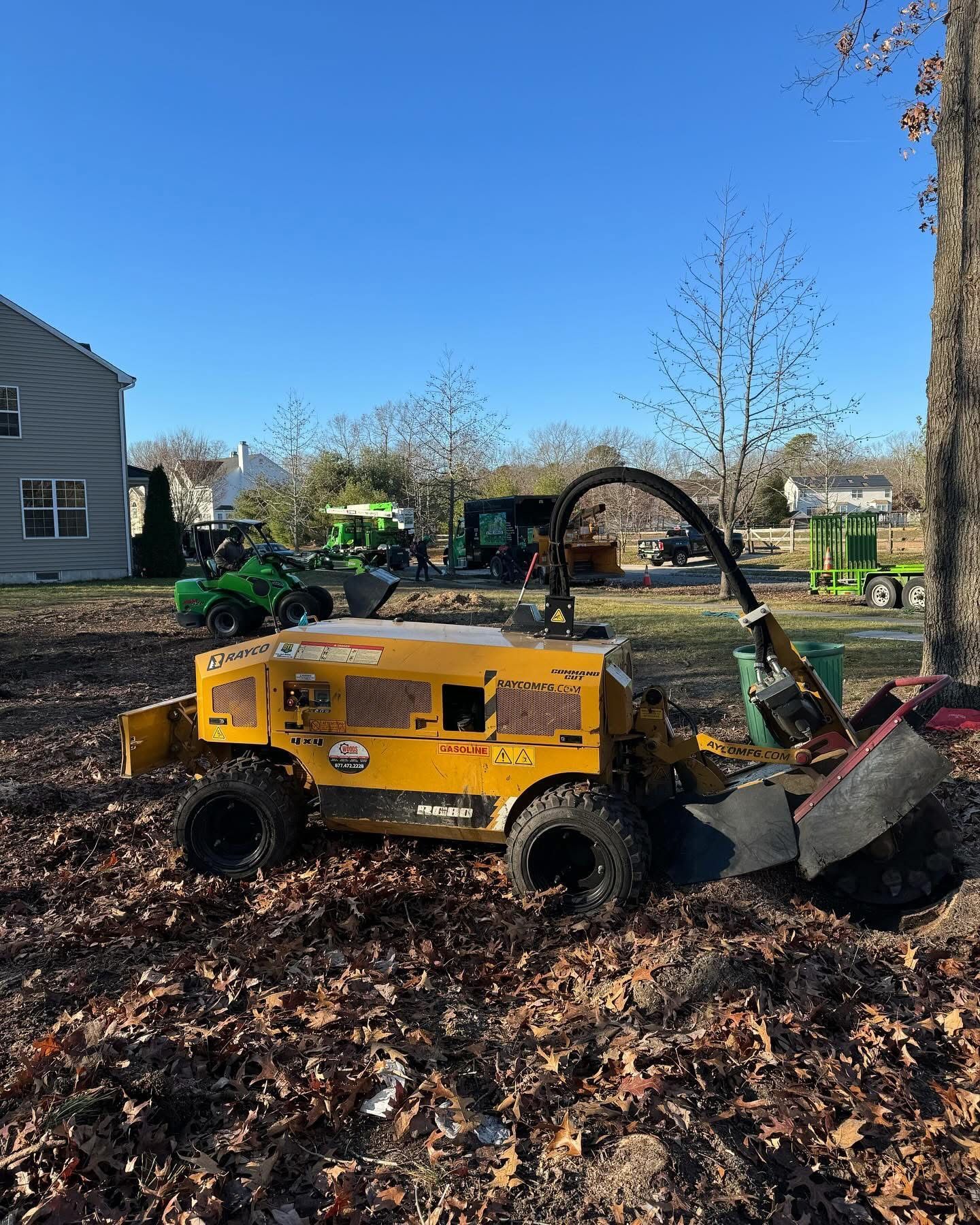 A yellow tractor is sitting on top of a pile of leaves next to a tree.