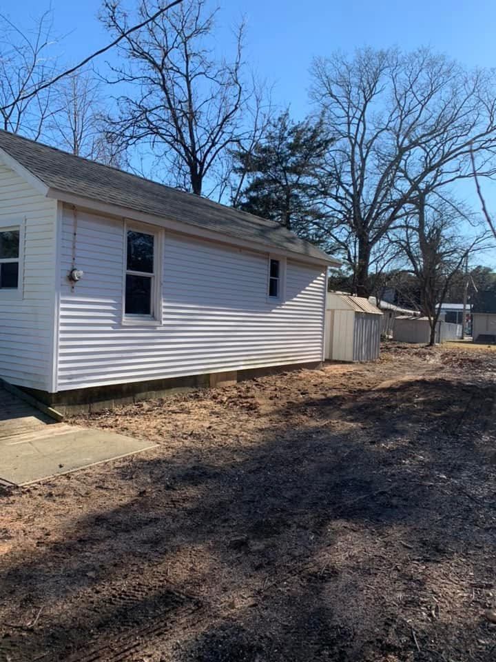 A small white house is sitting in the middle of a dirt field.