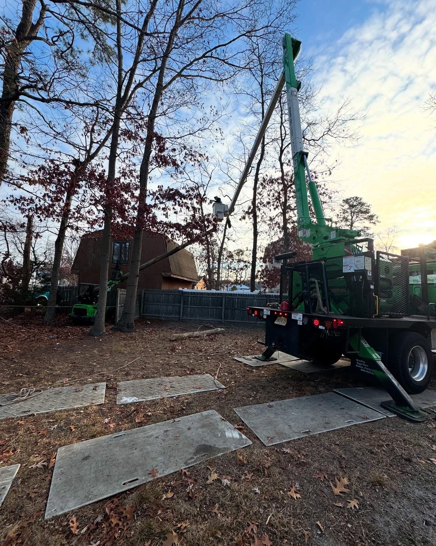 A green crane is sitting on top of a truck in a yard.