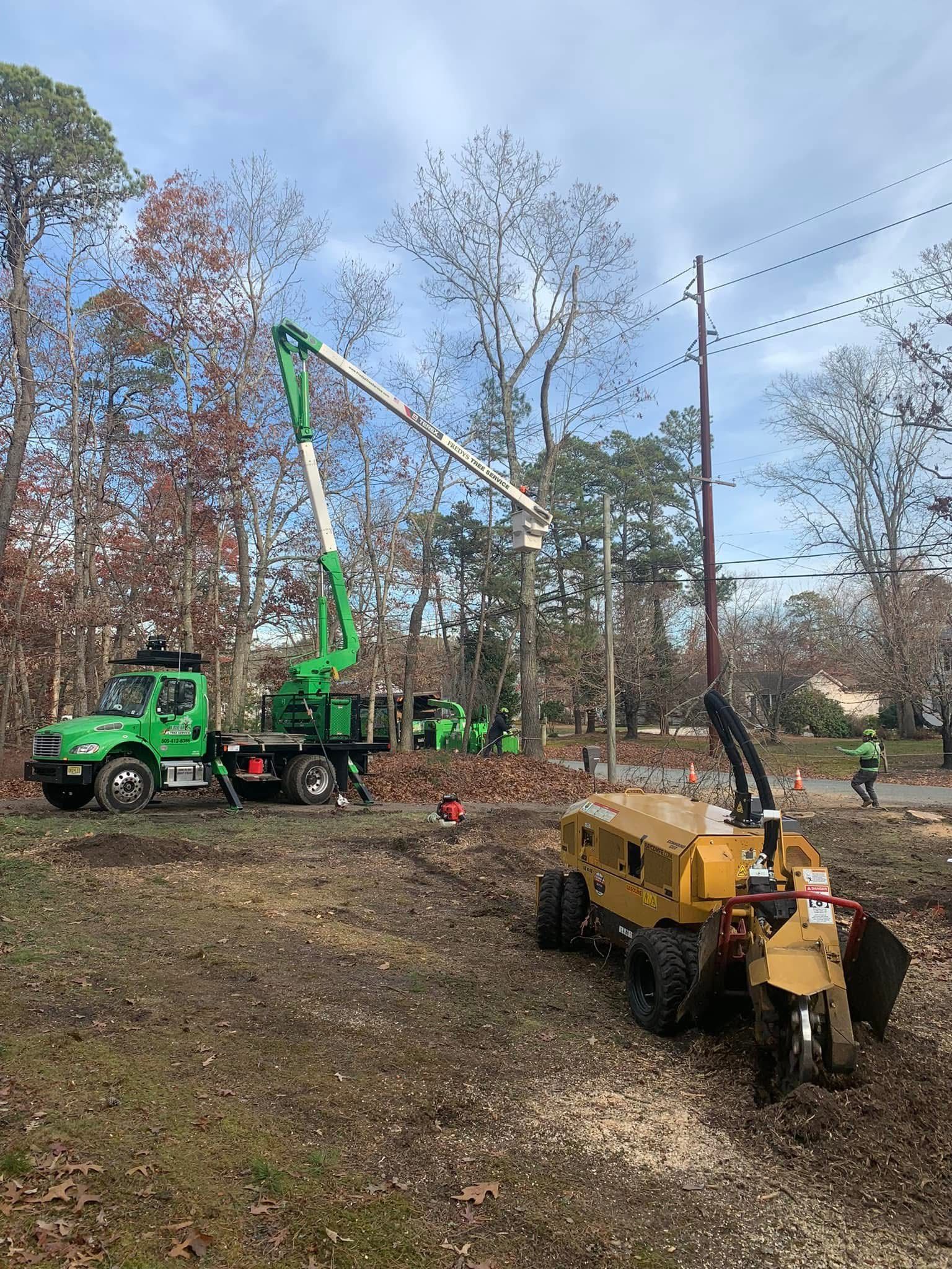 A tree stump grinder is sitting next to a truck in a field.