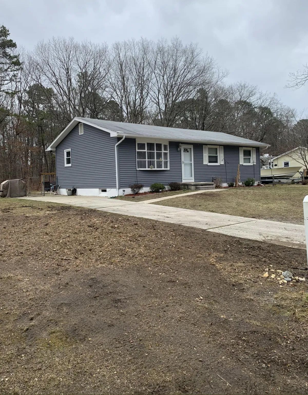 A blue house with white trim is sitting on top of a dirt hill.