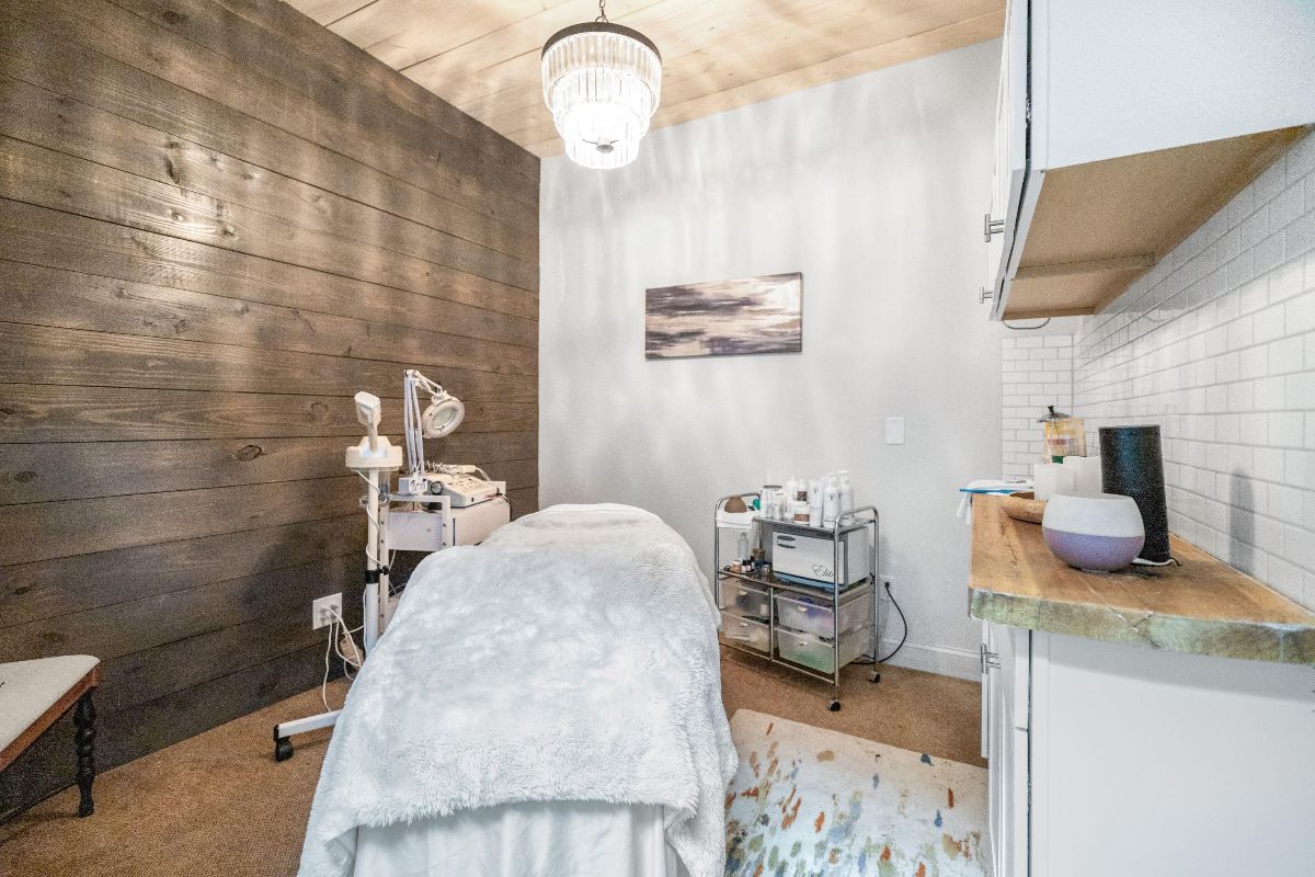Cozy spa treatment room with massage table, wood accent wall, and soft lighting