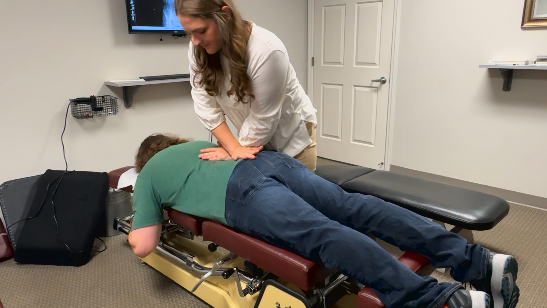 Chiropractor adjusting a patient lying face down on a treatment table in a clinic room