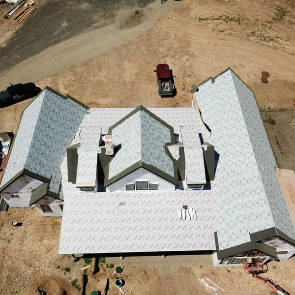 Aerial view of a house under construction with a partially completed roof and a truck parked nearby.