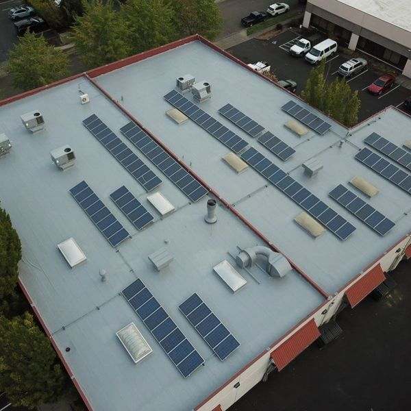 Aerial view of a commercial building rooftop with rows of solar panels and various ventilation systems.
