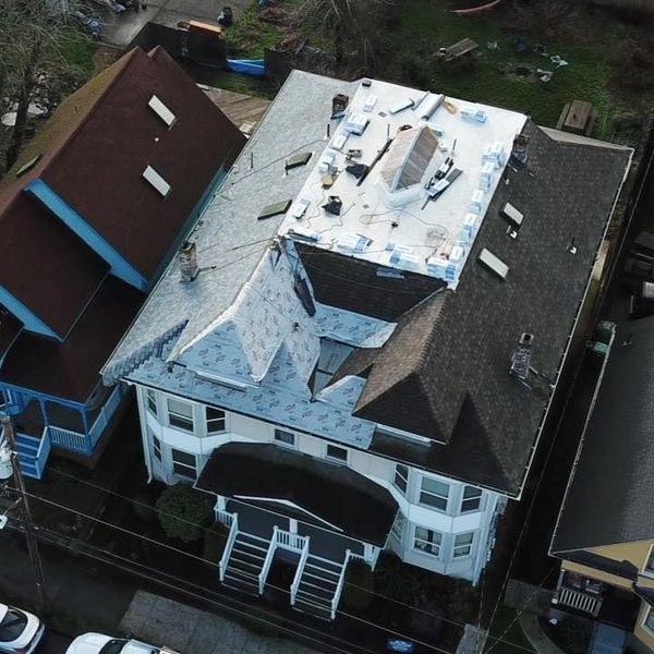 An aerial view of a multi-story house with a partially replaced roof.