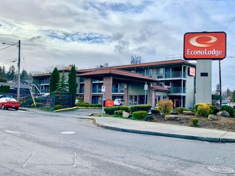 Econo Lodge hotel exterior with orange sign. Building has multiple floors, overcast sky, street in foreground.
