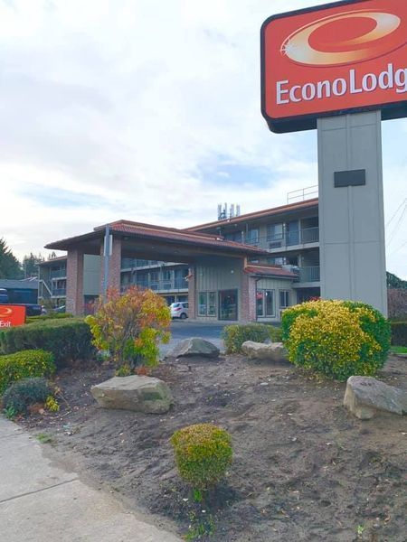 Econo Lodge hotel exterior with sign and landscaping under a cloudy sky.