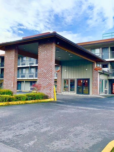 Hotel entrance with brick columns, canopy, and multiple-story building.