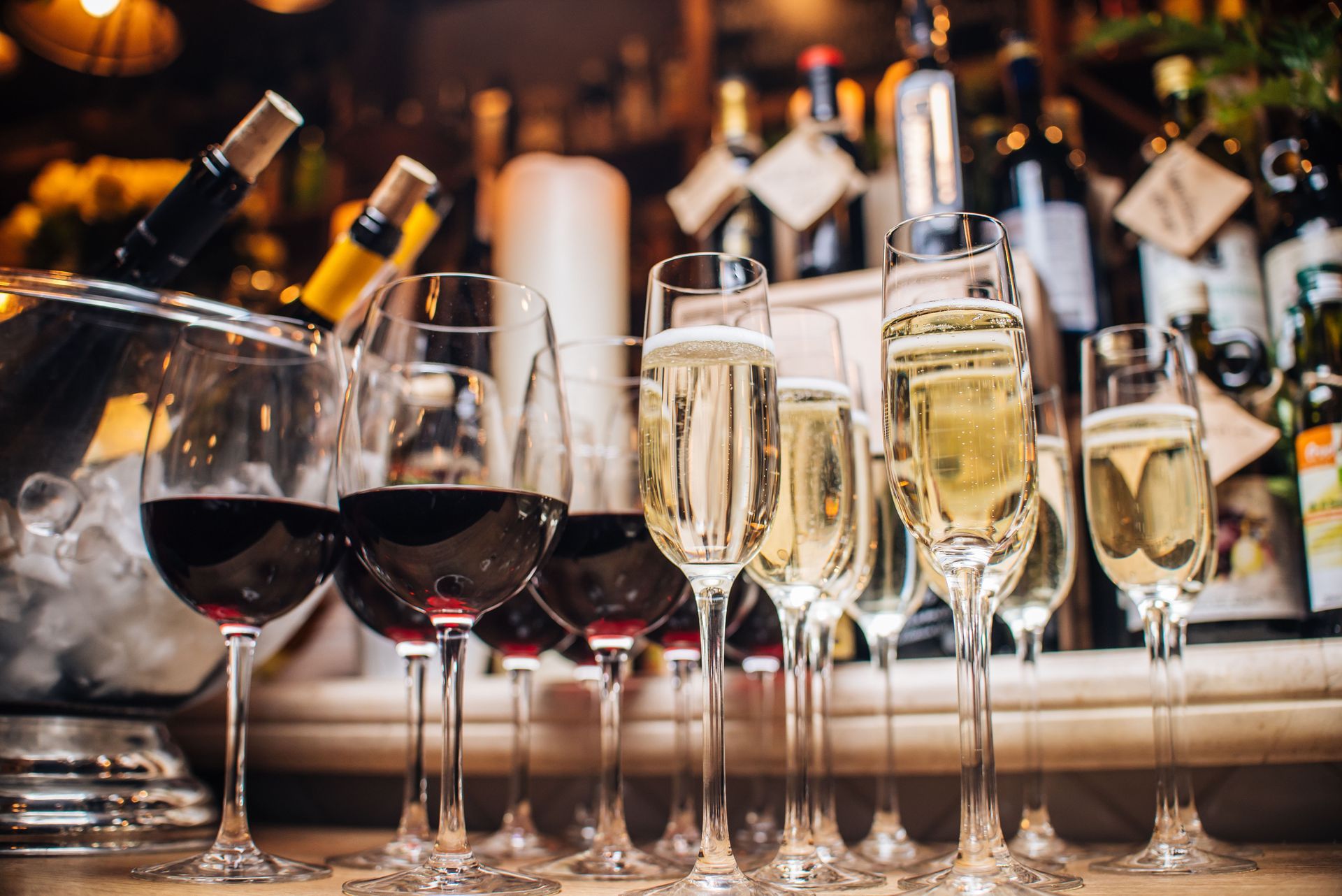 A row of wine glasses filled with wine and champagne on a table.