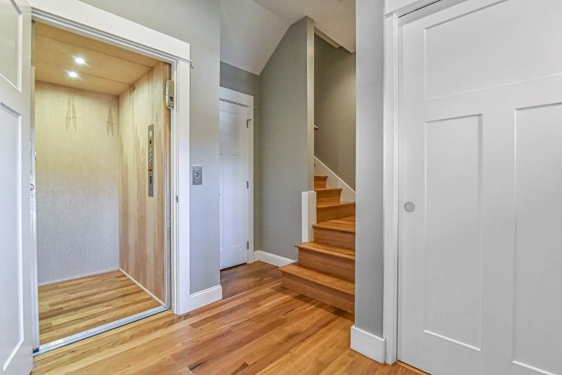 A hallway with an elevator and stairs in a house.