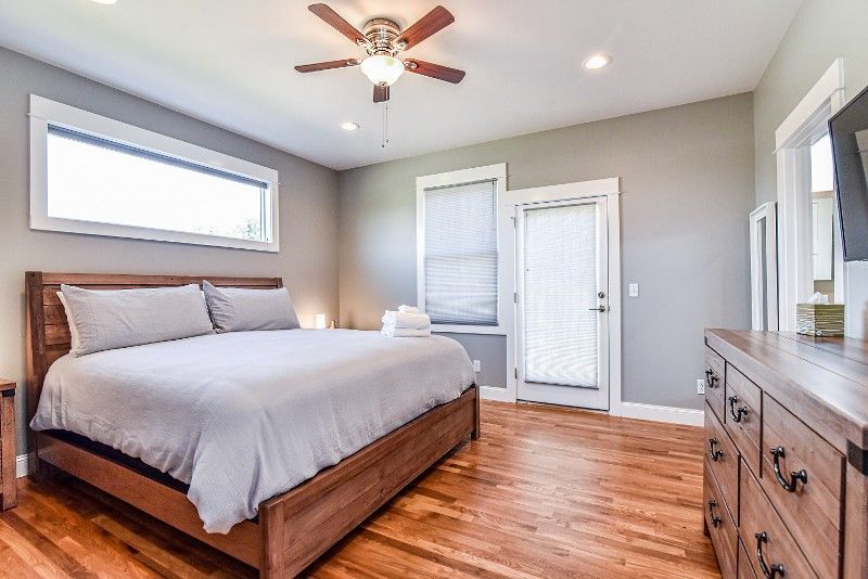 A bedroom with a king-size bed, dresser, mirror, and ceiling fan.