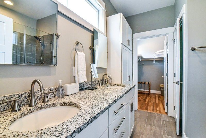 A bathroom with two sinks, a mirror, and a walk -in closet.