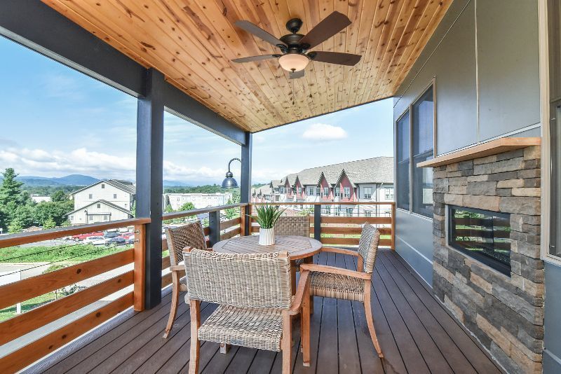 A porch with a table and chairs and a ceiling fan.