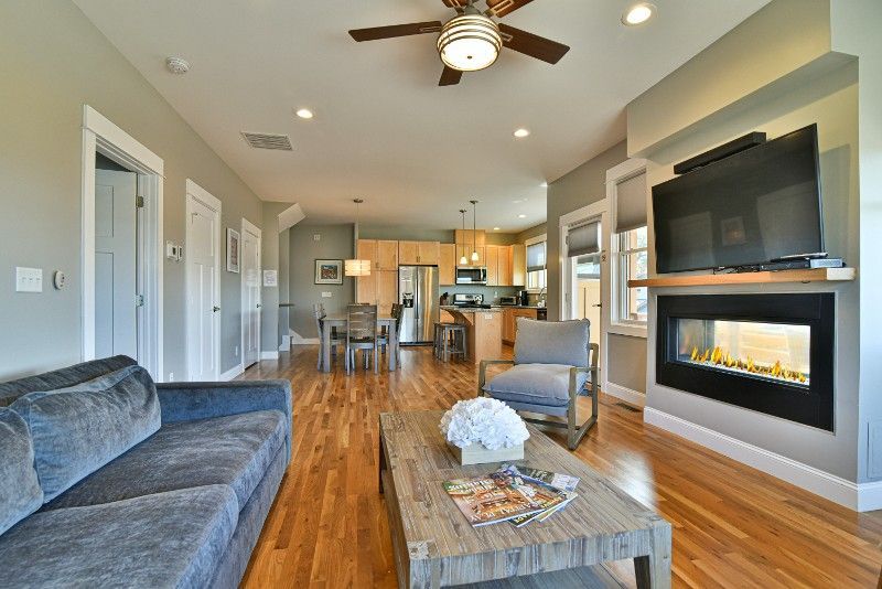 A living room with a couch, fireplace, television, and ceiling fan.