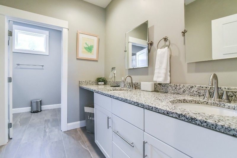 A bathroom with two sinks, a mirror and a toilet.