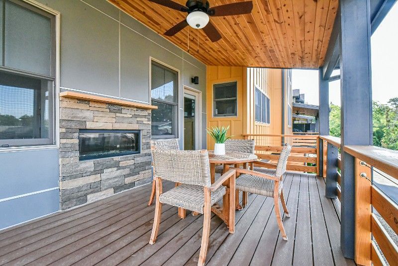 A wooden deck with a table and chairs and a ceiling fan.