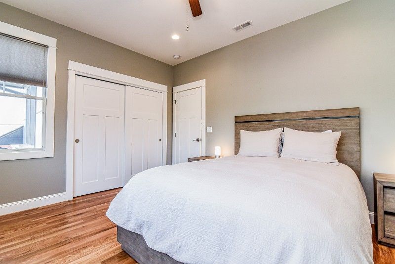 A bedroom with a bed, nightstand, closet and window.