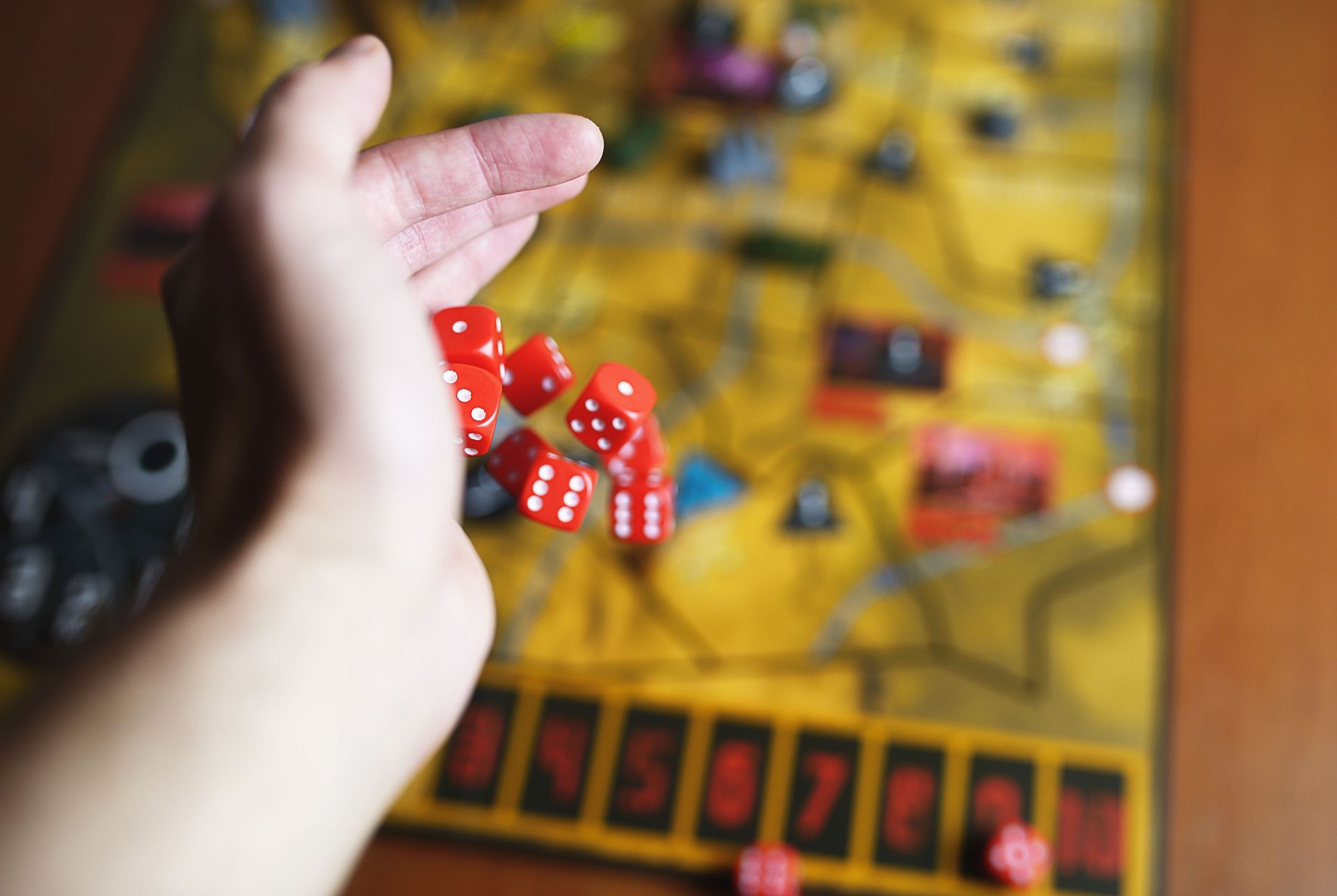 A person is playing a board game with red dice.