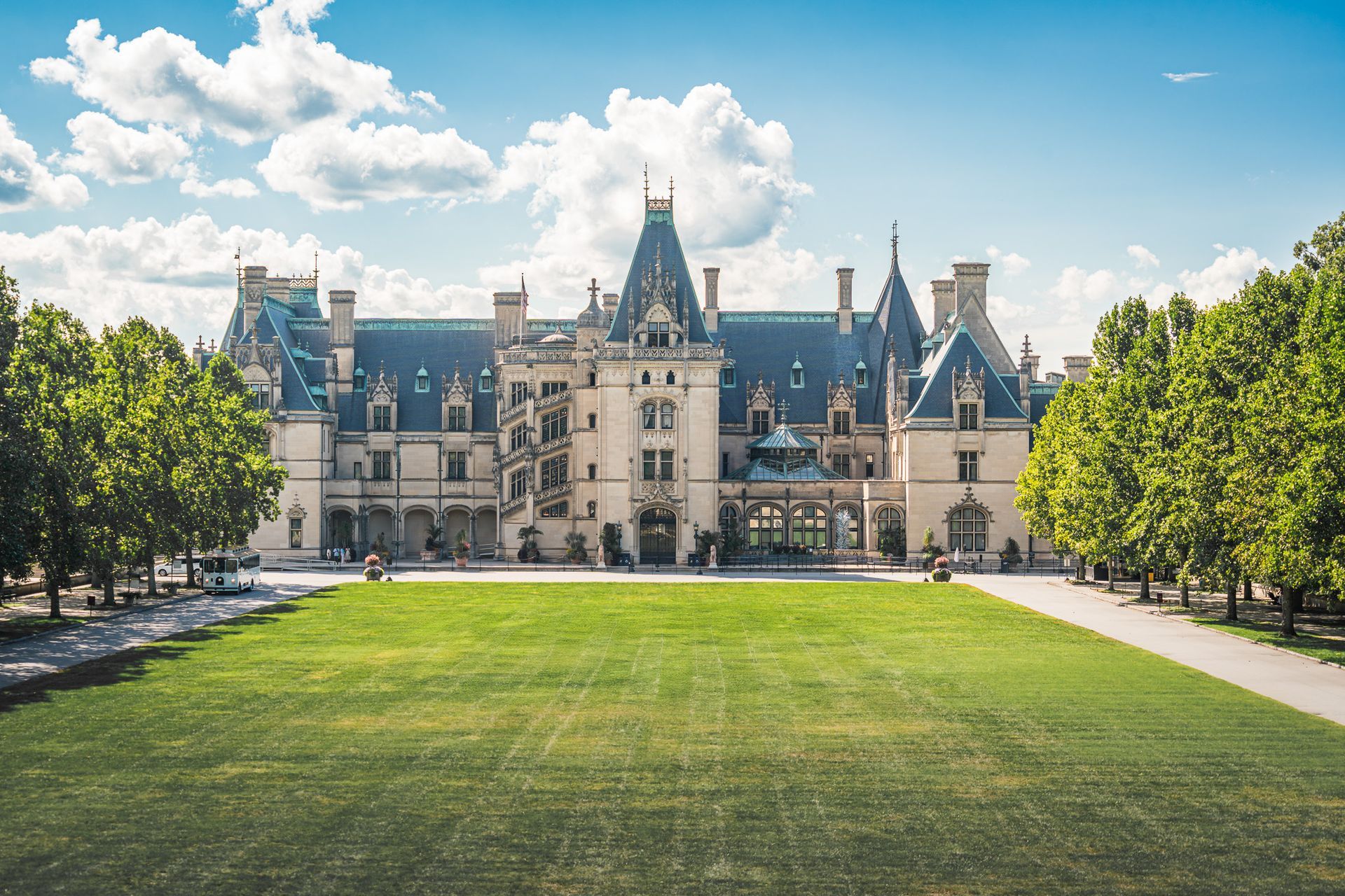 A large castle sitting on top of a lush green field surrounded by trees.