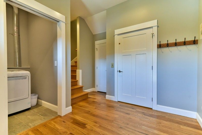 A hallway with hardwood floors, a washer and dryer, and stairs.