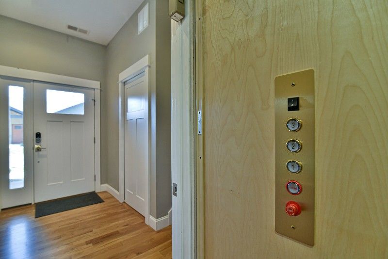 A hallway with a door and a elevator in the background.