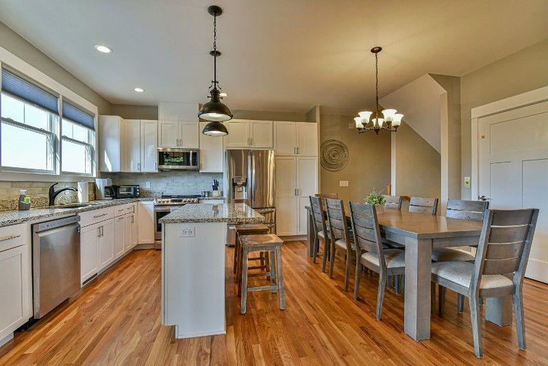 A kitchen and dining room in a house with hardwood floors and stainless steel appliances.