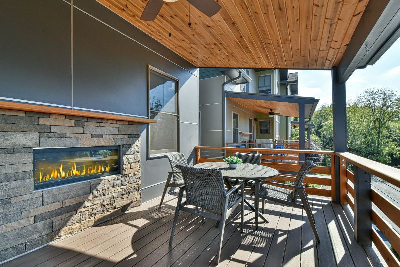A deck with a fireplace and a table and chairs on it.