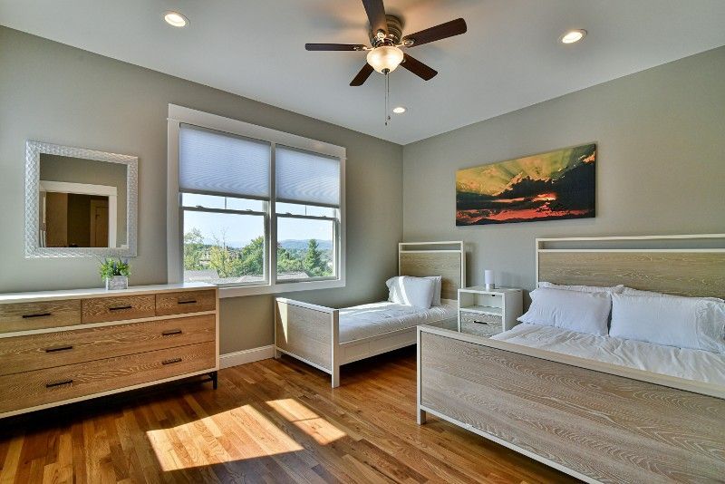 A bedroom with two beds, a dresser, a mirror, and a ceiling fan.