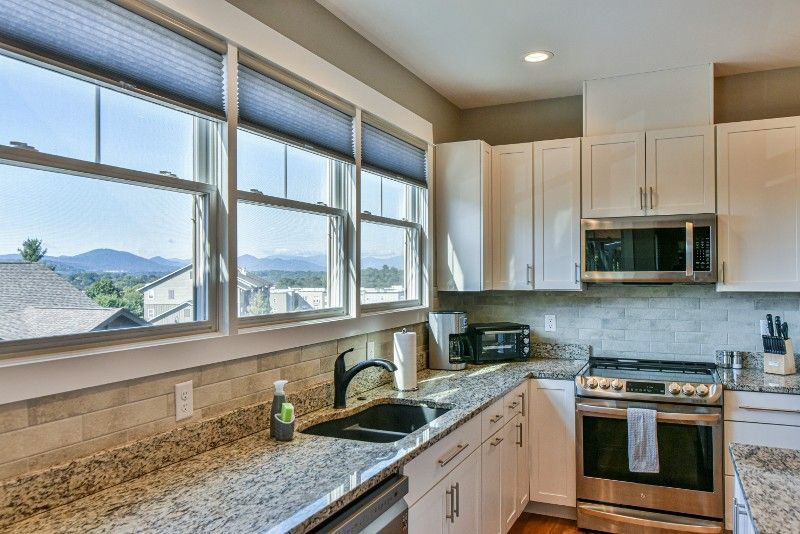 A kitchen with granite counter tops, stainless steel appliances, a sink, stove, and microwave.