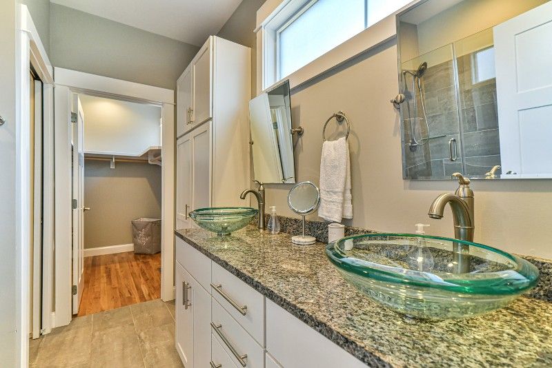 A bathroom with two sinks, a mirror, and a walk-in closet.