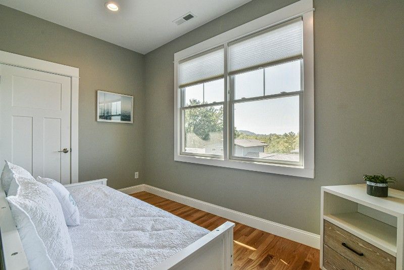 A bedroom with a day bed and two windows.