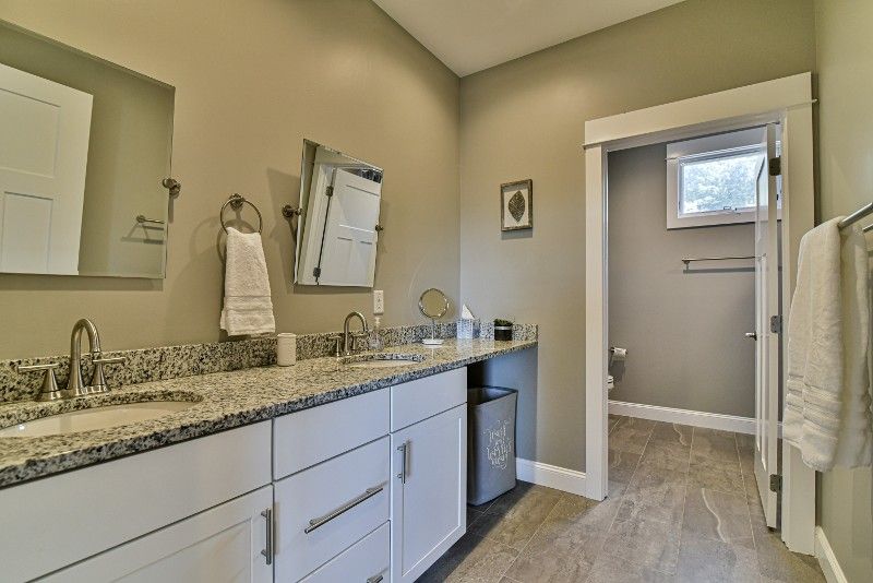 A bathroom with two sinks, two mirrors, and a toilet.