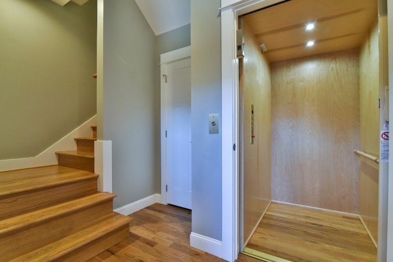 A hallway with wooden stairs and an elevator.