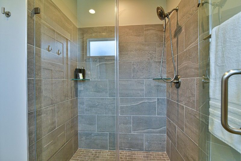 A bathroom with a walk in shower and a glass door.