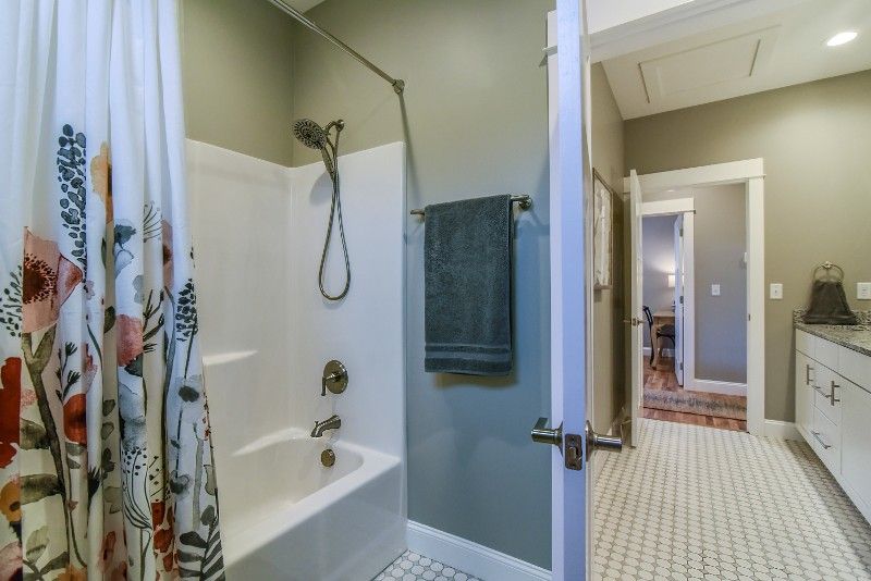 A bathroom with a bathtub and shower with a floral shower curtain.