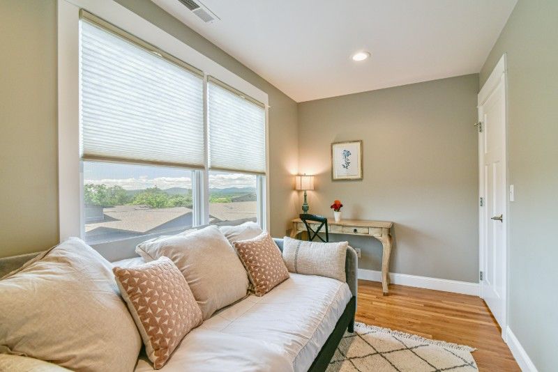 A living room with a couch, desk, and two windows.
