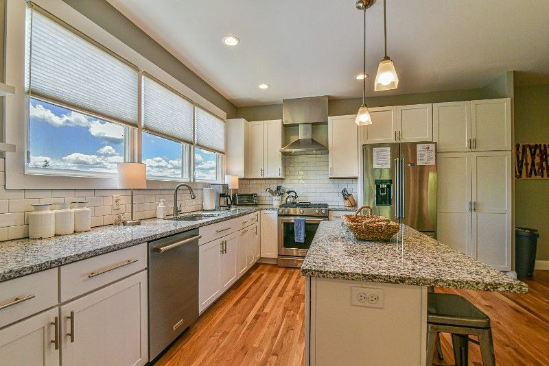 A kitchen with white cabinets, granite counter tops, stainless steel appliances, and hardwood floors.