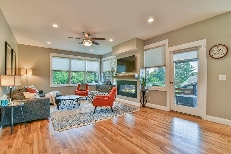 A living room with hardwood floors, a couch, chairs, and a fireplace.