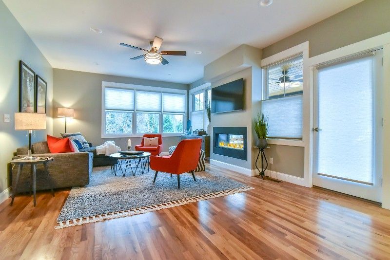 A living room with hardwood floors, a couch, chairs, and a fireplace.